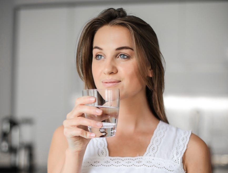 woman in white floral lace sleeveless dress holding clear drinking glass